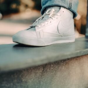 Detailed close-up of a white sneaker on an urban ledge, emphasizing modern footwear style.