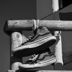 Striped sneakers hanging on a wooden fence in monochrome.