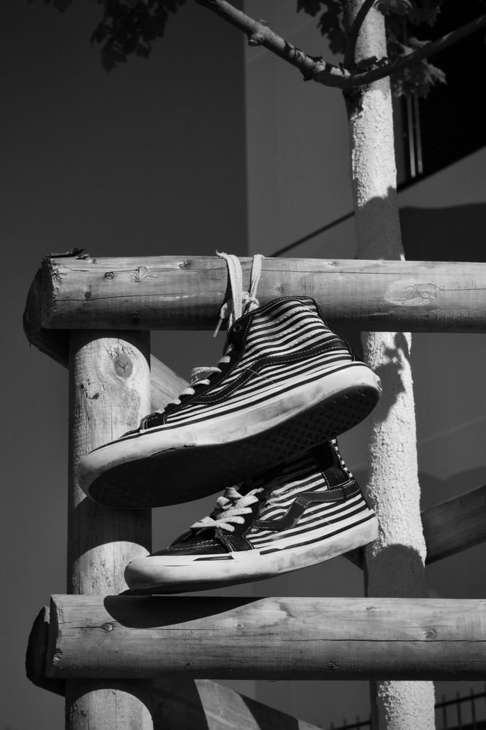 Striped sneakers hanging on a wooden fence in monochrome.